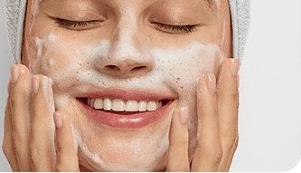 A woman washing her face with a cleanser